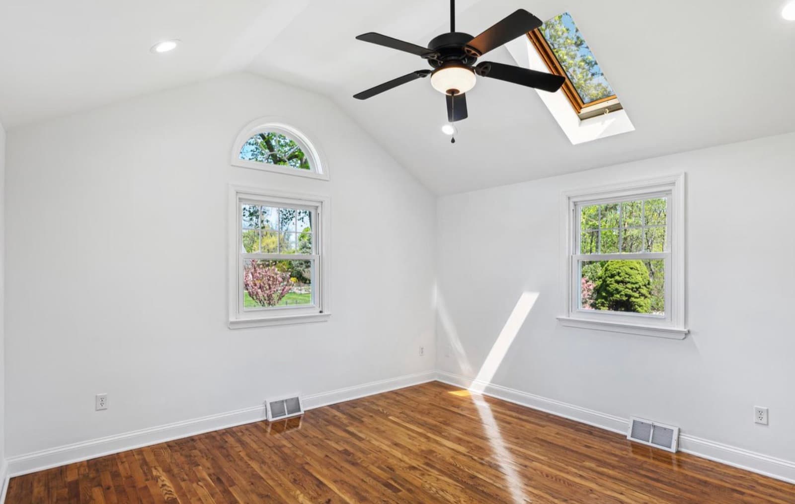 Bedroom with vaulted ceiling and arched window