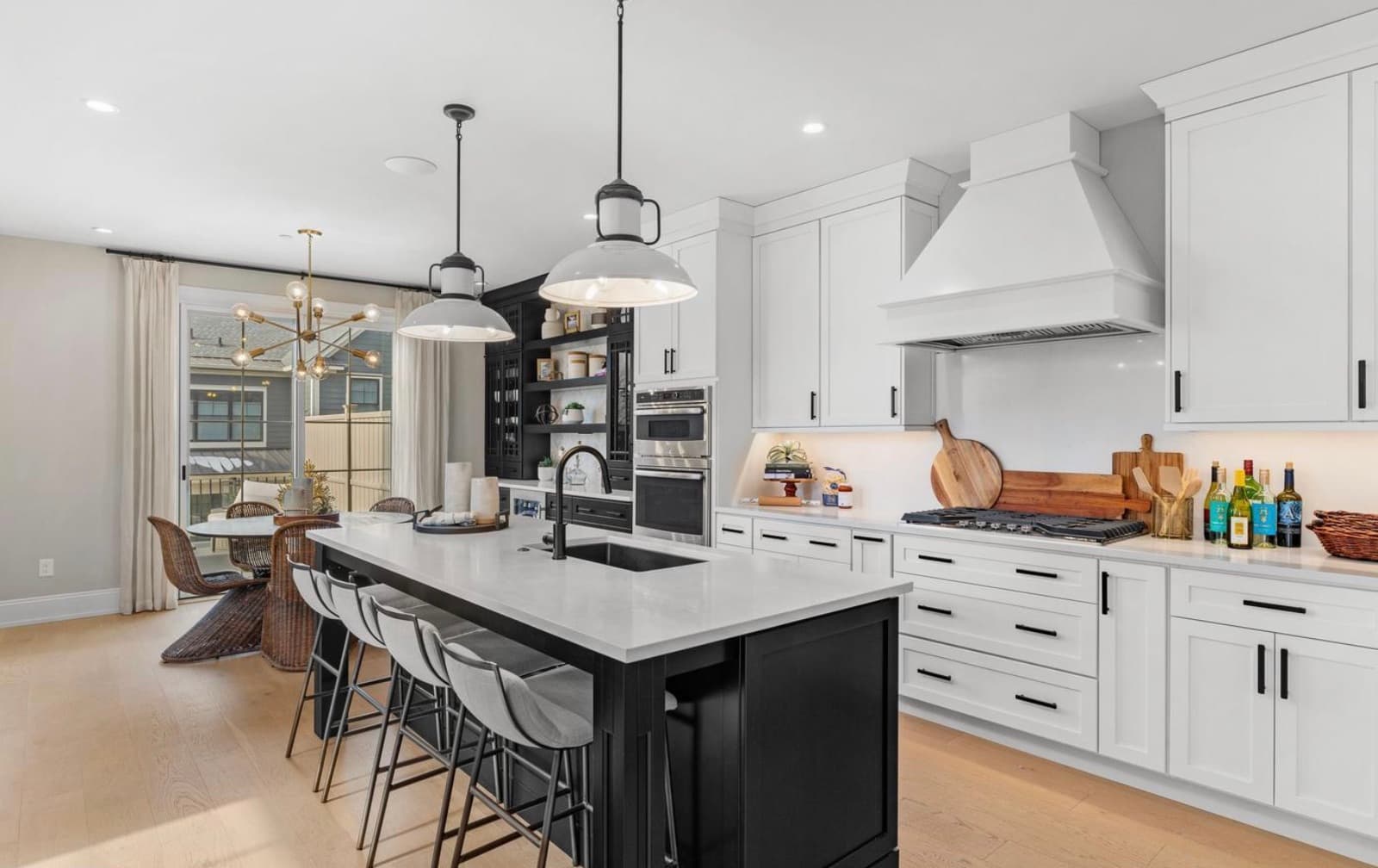 Kitchen with marble island, white cabinets, and range hood